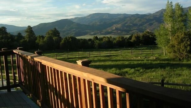 A wooden deck overlooking a grassy field with distant mountains. - Star Mesa 2 Bedroom Holiday Home By Pinon Vacation Rentals (Howard)