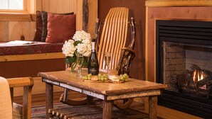 A wooden table with a bottle of wine, glasses, and grapes. - Robert Frost Mountain Cabins (Ripton)