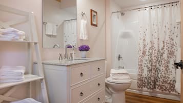 Une salle de bain équipée d’un lavabo, d’un miroir, de toilettes et d’un rideau de douche.