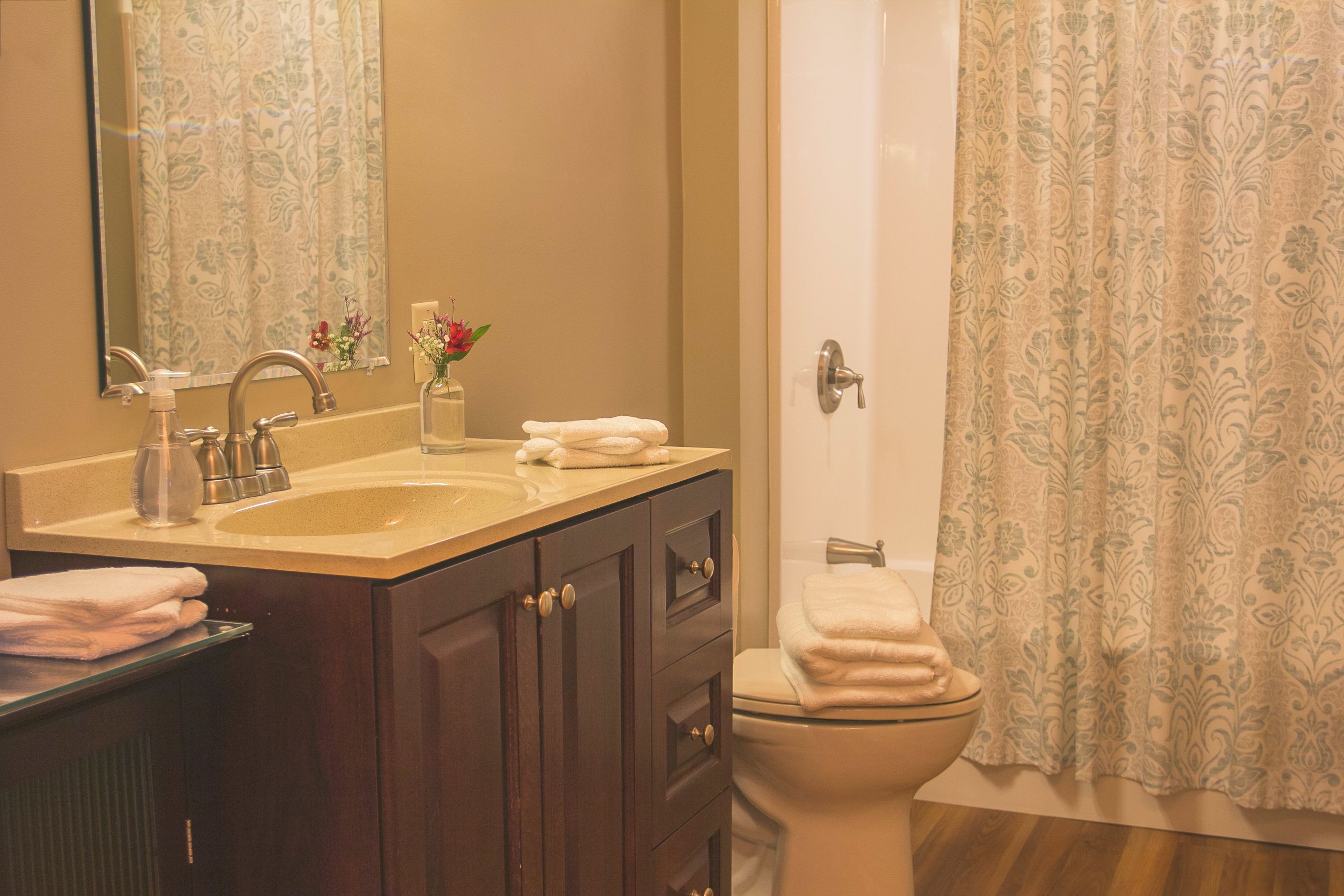 A bathroom with a sink, mirror, cabinet, toilet, and shower curtain.