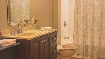 A bathroom with a sink, mirror, cabinet, toilet, and shower curtain.