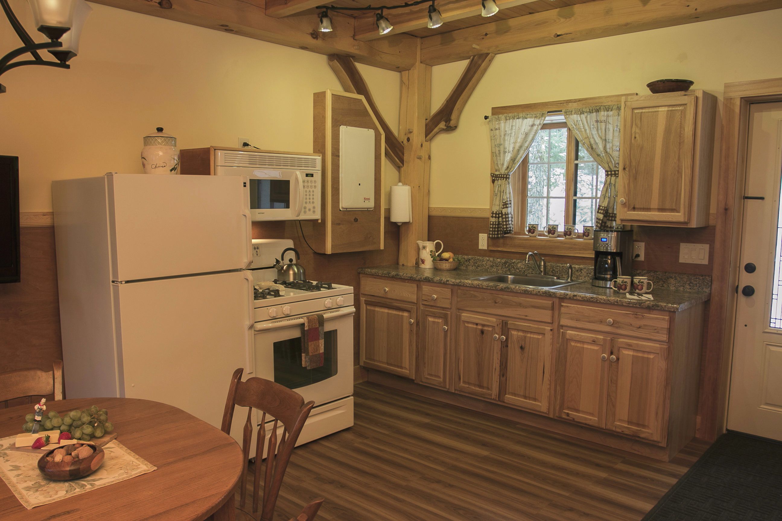 Une cuisine avec des meubles de rangement en bois, un réfrigérateur, une cuisinière et une table à manger avec des chaises.