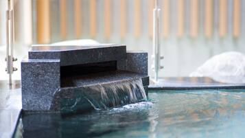Ein Wasserspiel mit einer Steinstruktur und einem Glasgeländer.