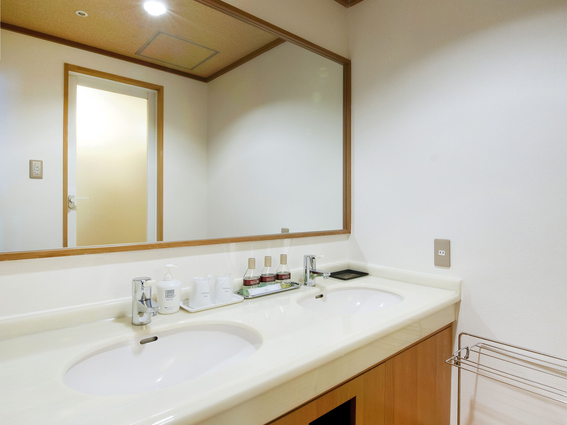 Un baño con dos lavabos, un espejo y artículos de aseo.