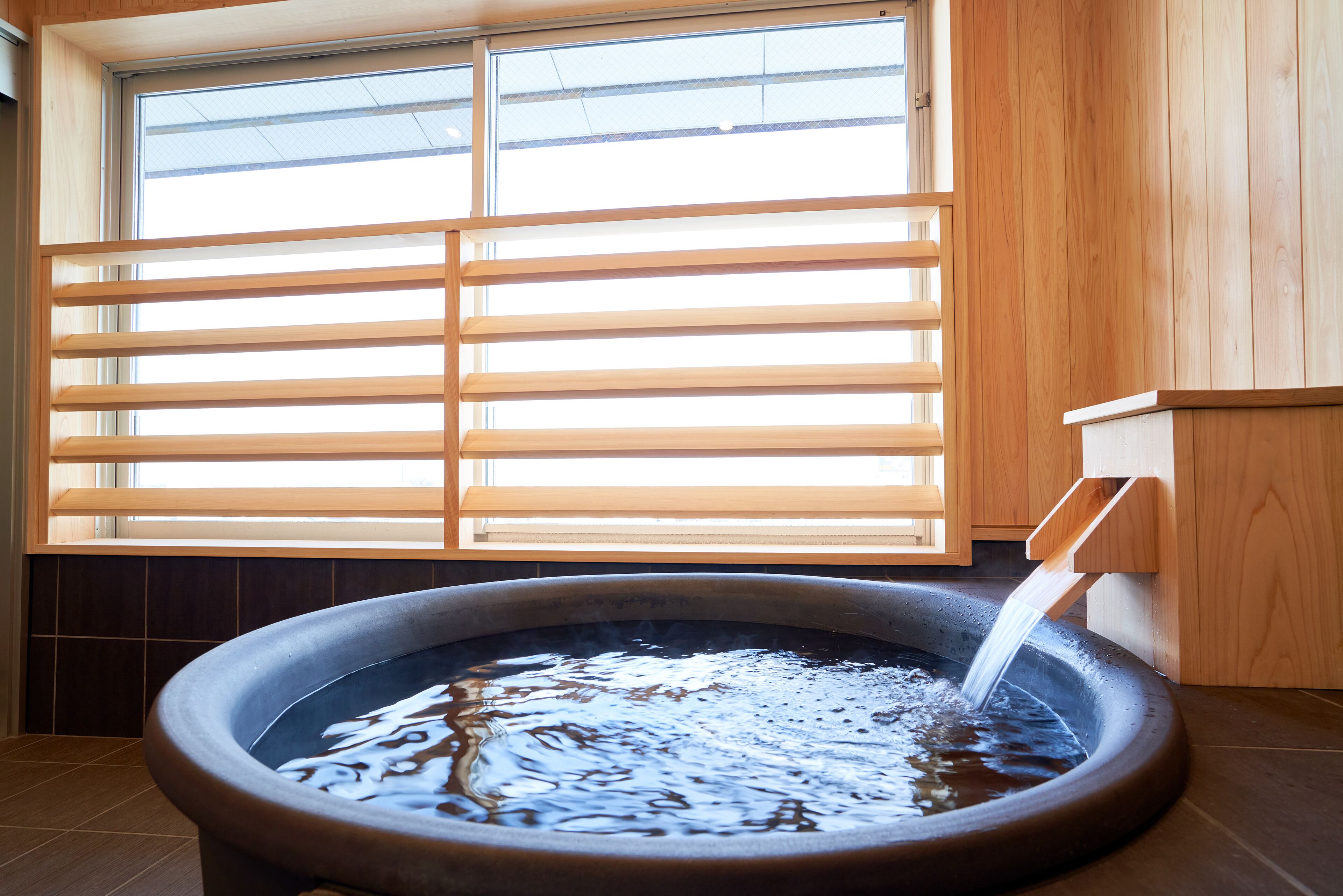 A hot tub with a wooden structure and a window with blinds.