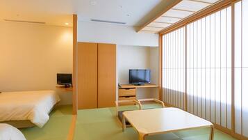 Habitación de hotel con dos camas, televisión, escritorio y piso de esteras de tatami.