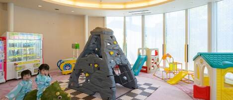 A children's play area with climbing structures, a slide, and a trampoline.