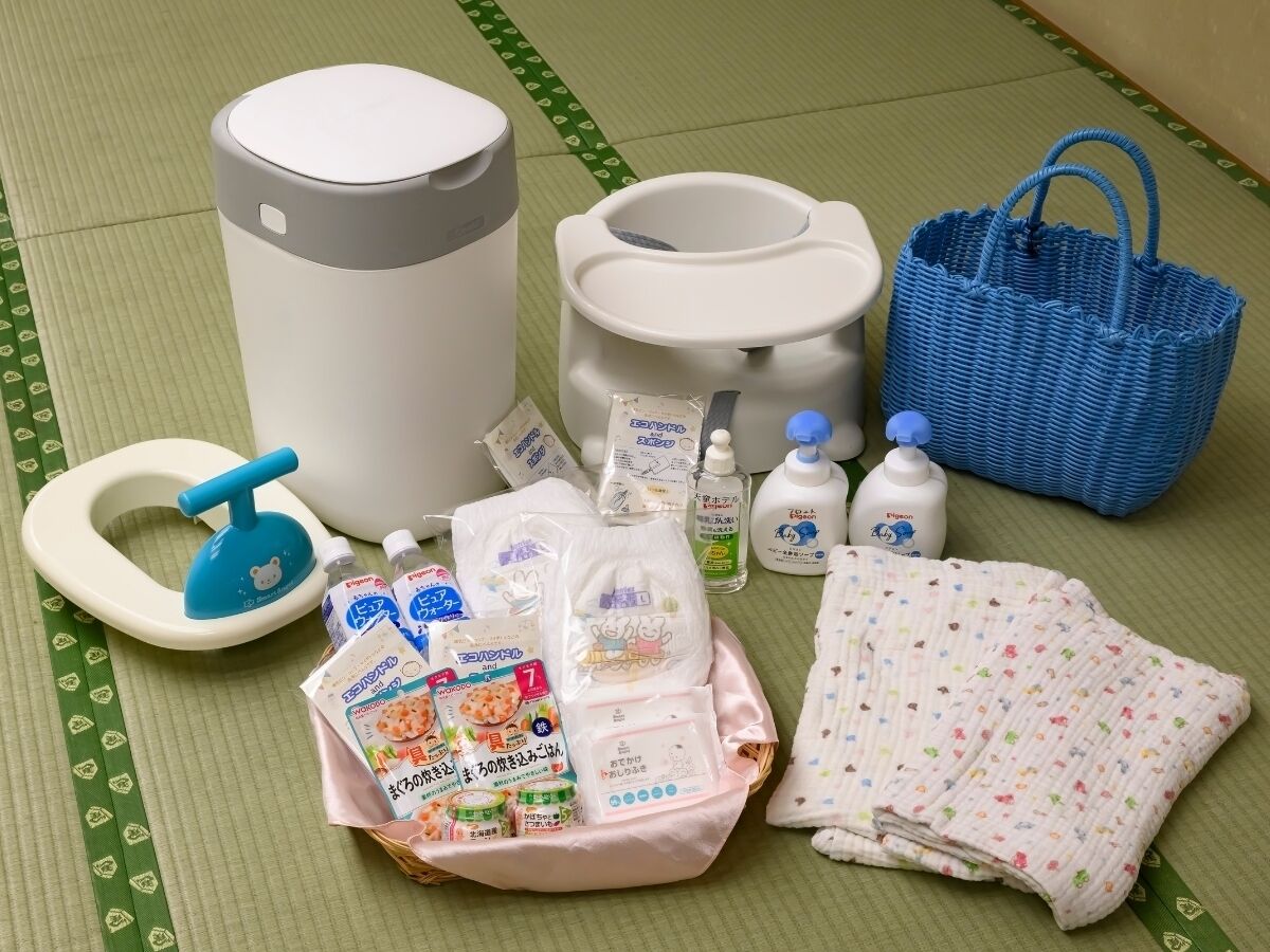 Una habitación con suelo de tatami, inodoro blanco, cesto de basura azul y cesta azul, además de diversos artículos de aseo.