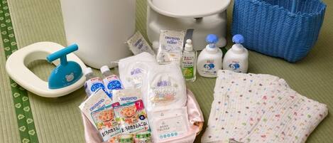 Una habitación con suelo de tatami, inodoro blanco, cesto de basura azul y cesta azul, además de diversos artículos de aseo.