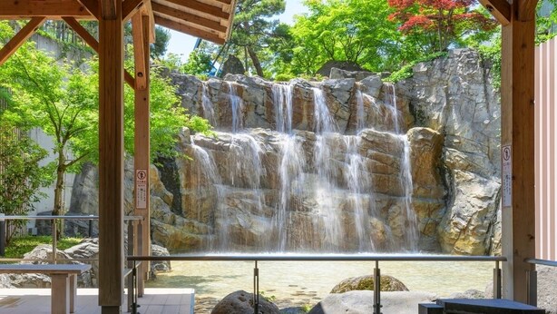 Una cascada en un espacio cubierto con una piscina al frente.