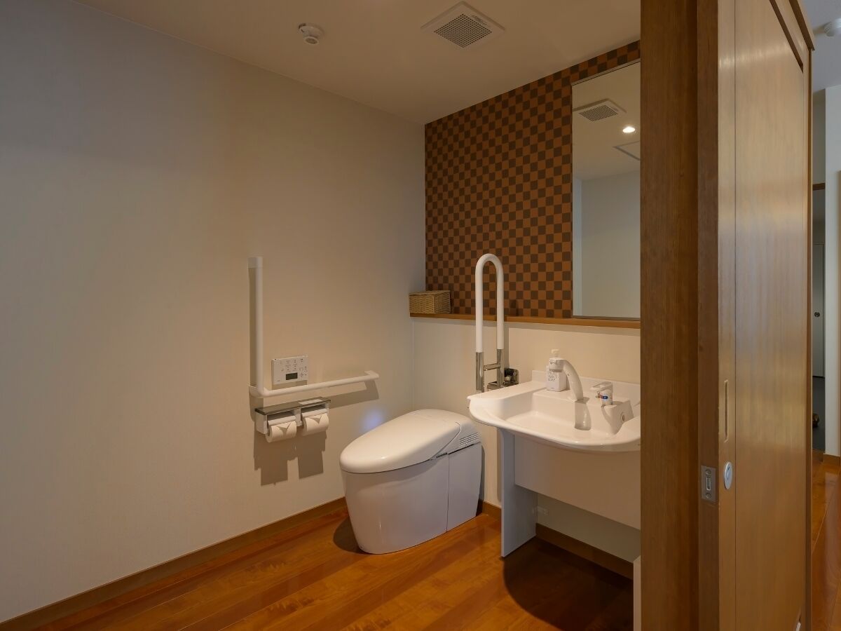 A bathroom with a toilet, sink, and mirror.