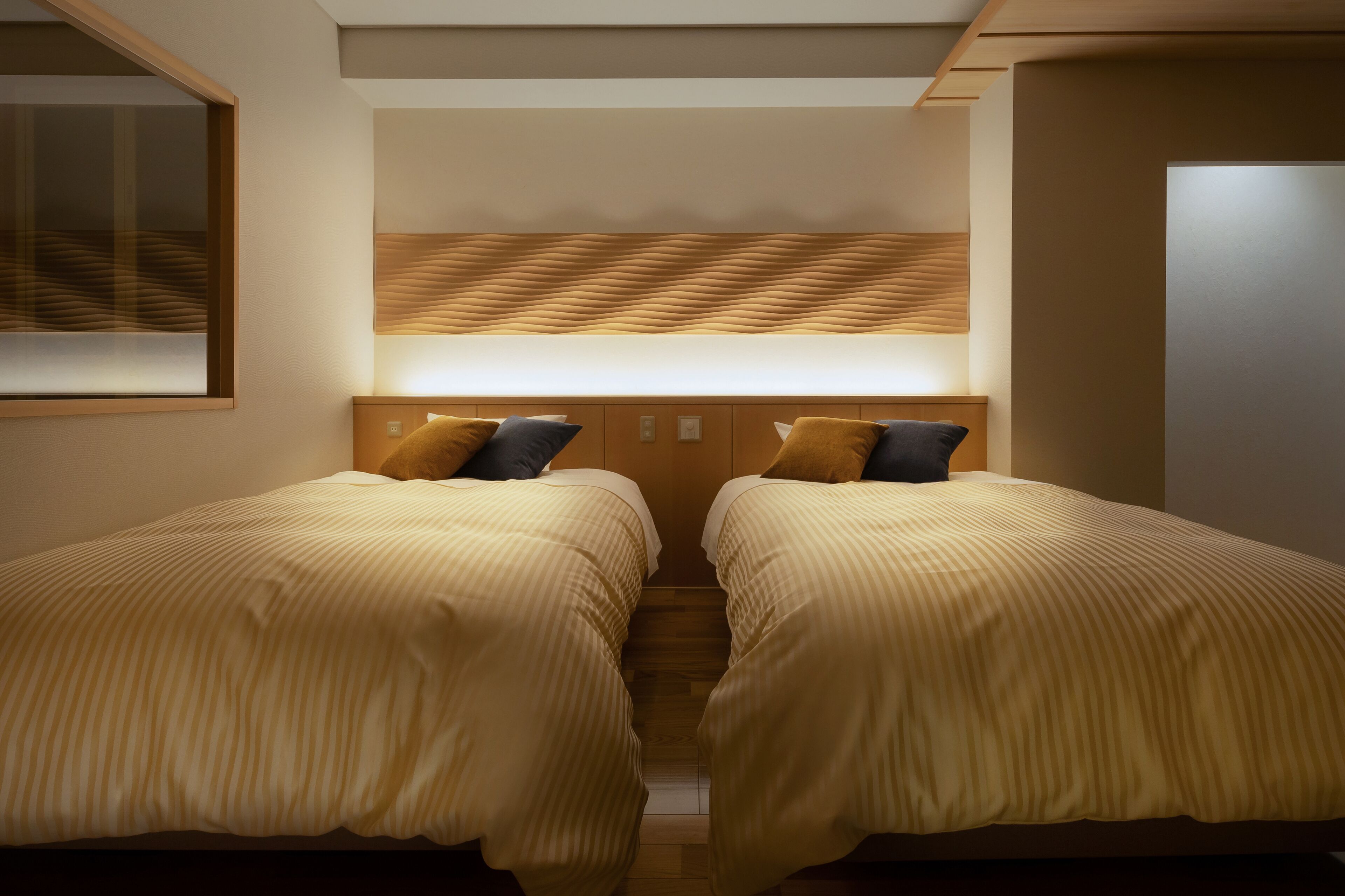 Una habitación de hotel con dos camas, un cabecero de madera y una mesita de noche.