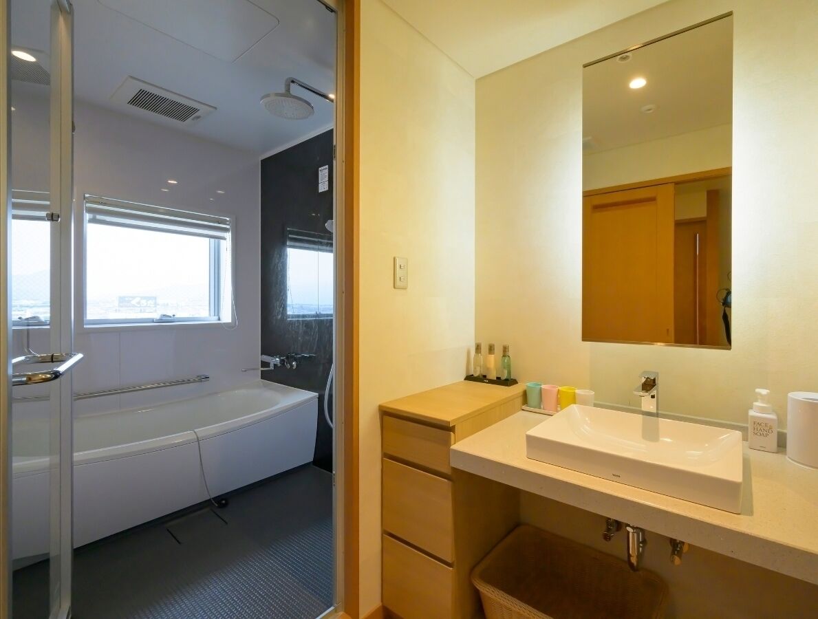 Un baño moderno con bañera, un espejo grande y un tocador con artículos de aseo.