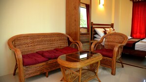 Una habitación con sofá, dos sillones, una mesita y cama.