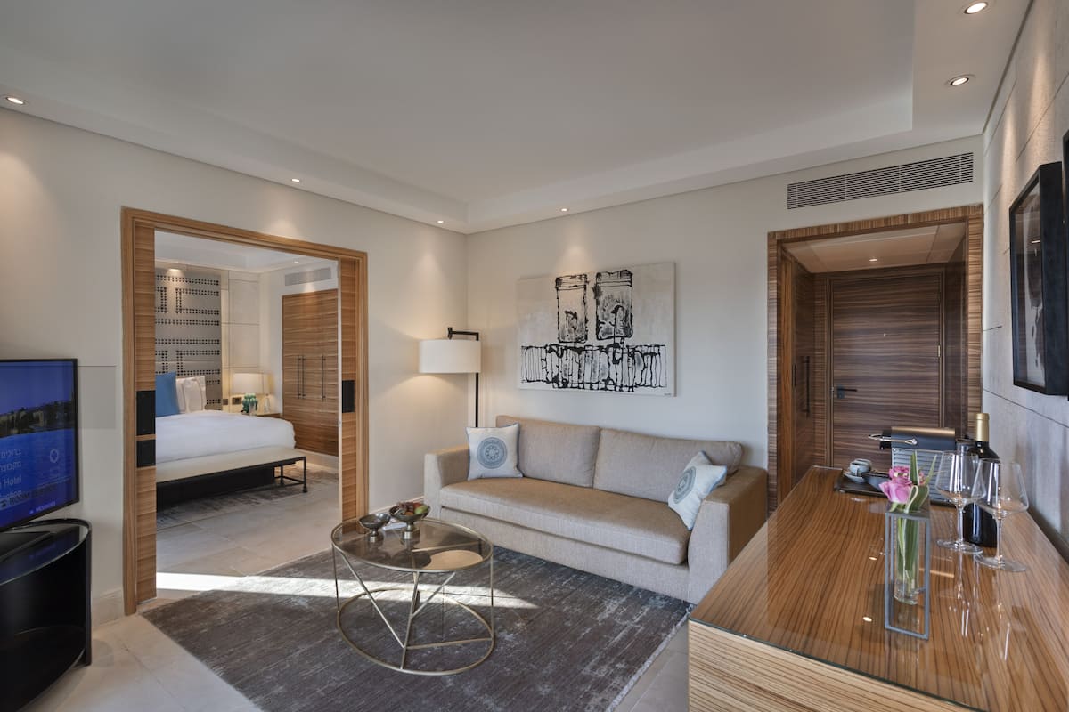 Una habitación de hotel moderna con sofá, mesa de centro, televisión y cama.
