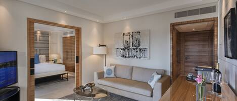 A modern hotel room with a sofa, a coffee table, a TV, and a bed.