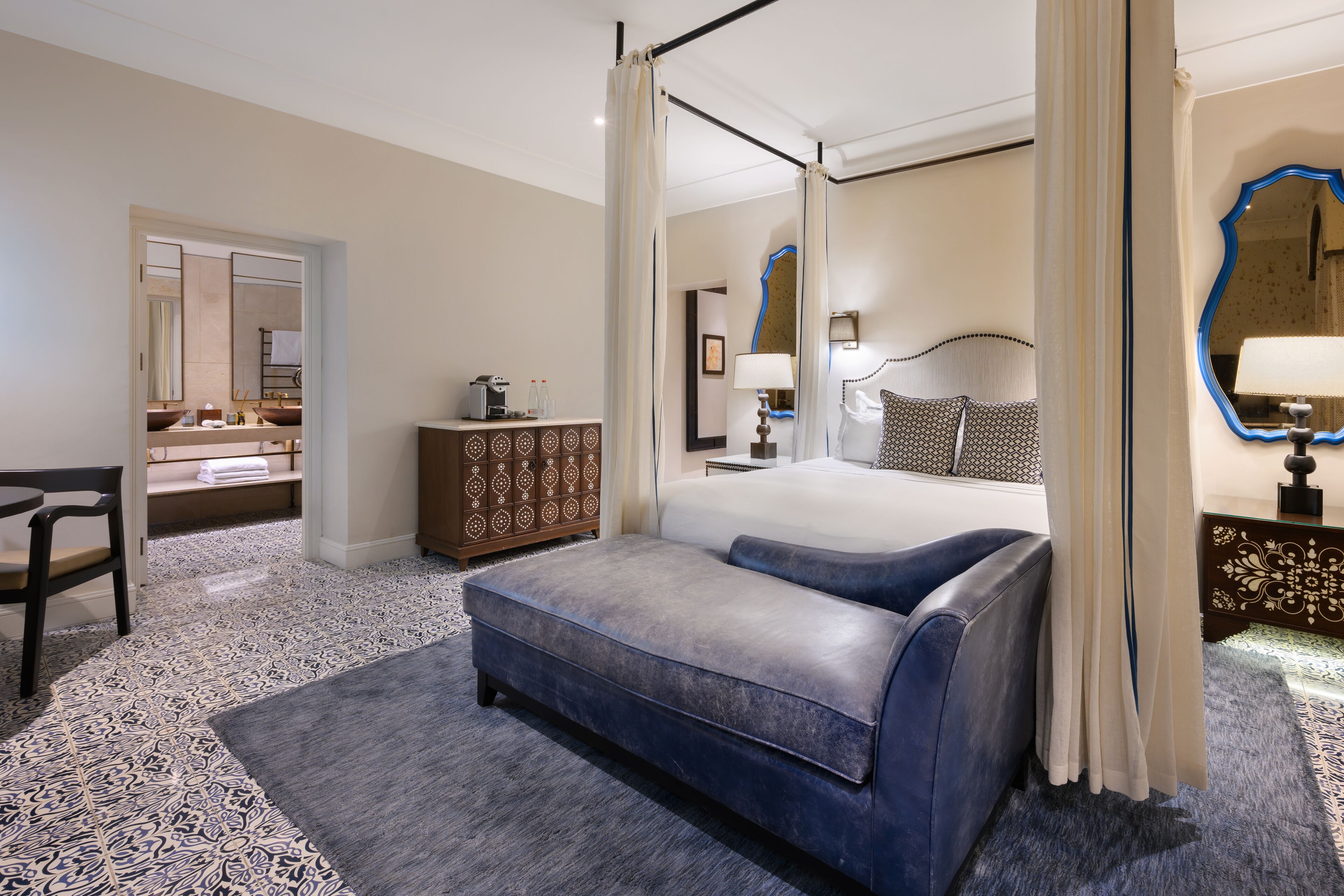 A bedroom with a bed, a bedside table, a dresser, a chair, and a mirror.