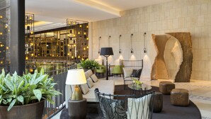 A modern lobby with a seating area, a staircase, and a decorative wall. - Orient by Isrotel exclusive (Jerusalem)
