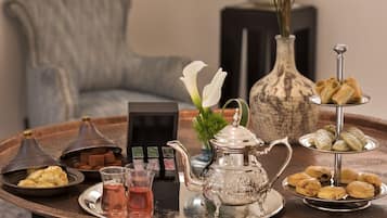 A tray with pastries, a teapot, and a glass of tea on a table.