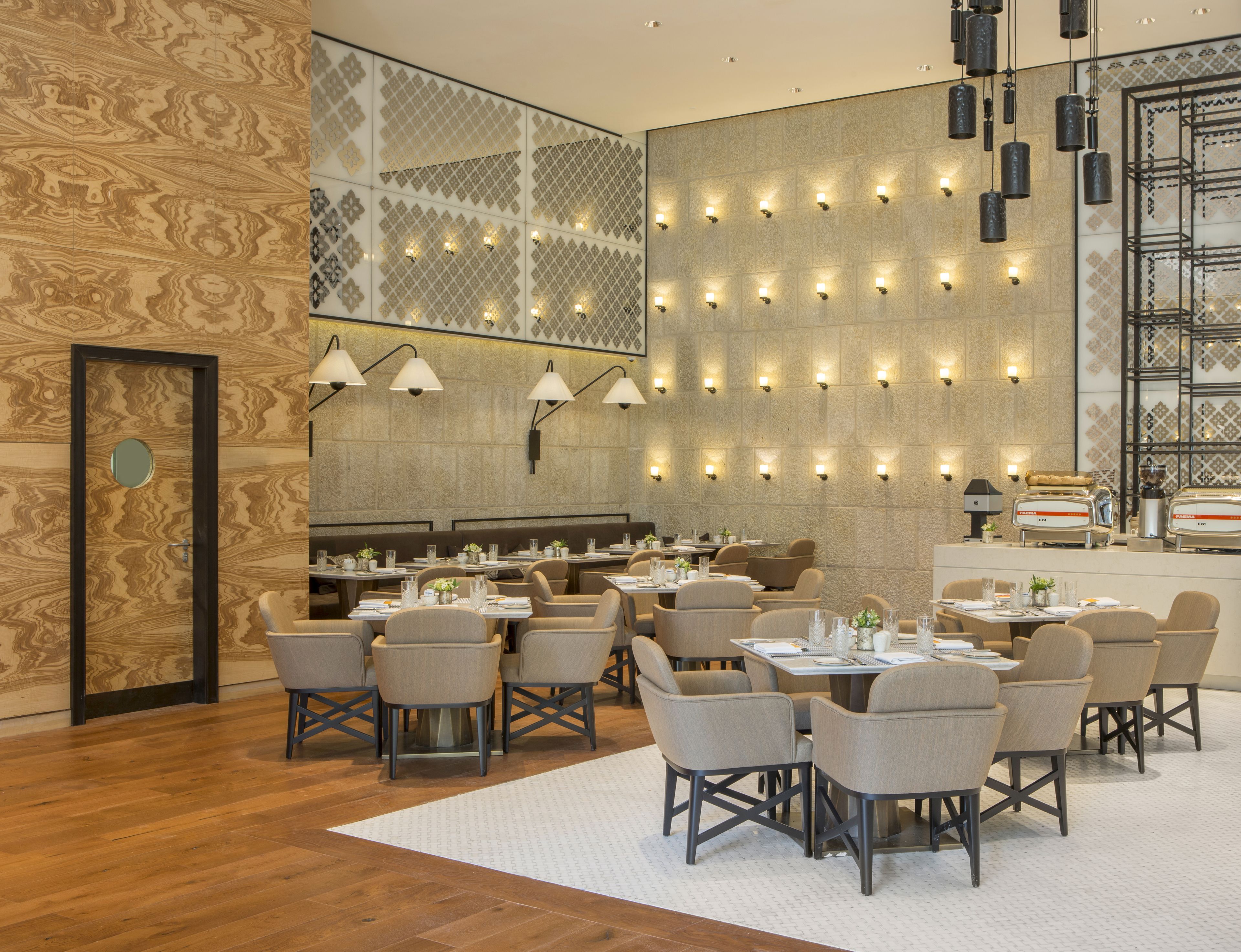 Un restaurante moderno con una pared con diseño, varias mesas y sillas.