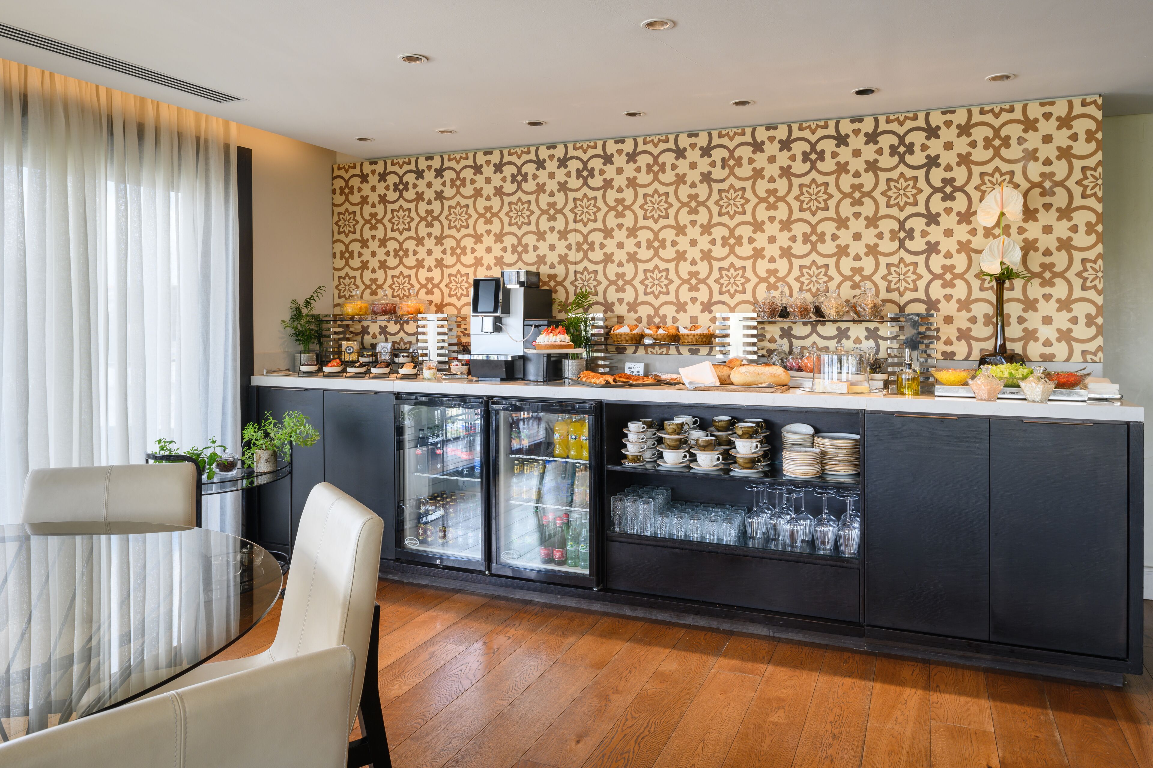 A modern breakfast bar with a patterned wallpaper, a glass-top table, and a seating area with a chair.