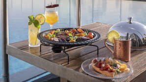 A dining table with a variety of dishes, drinks, and a view of a body of water. - Orient by Isrotel exclusive (Jerusalem)