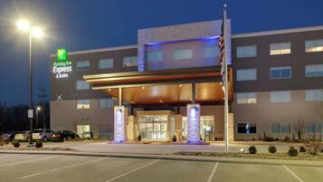 A Holiday Inn Express & Suites building with a modern design, featuring a prominent entrance with a covered walkway and stone pillars.