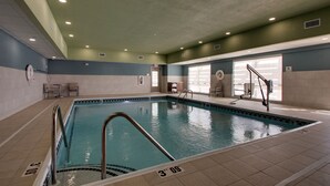 An indoor swimming pool with clear lane markings, a lifeguard chair, and a window providing natural light.