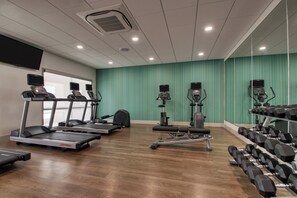 A gym with treadmills, elliptical machines, and dumbbells.