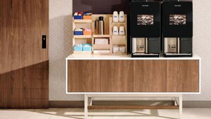 A modern kitchen with a wooden cabinet, coffee maker, and storage shelves.