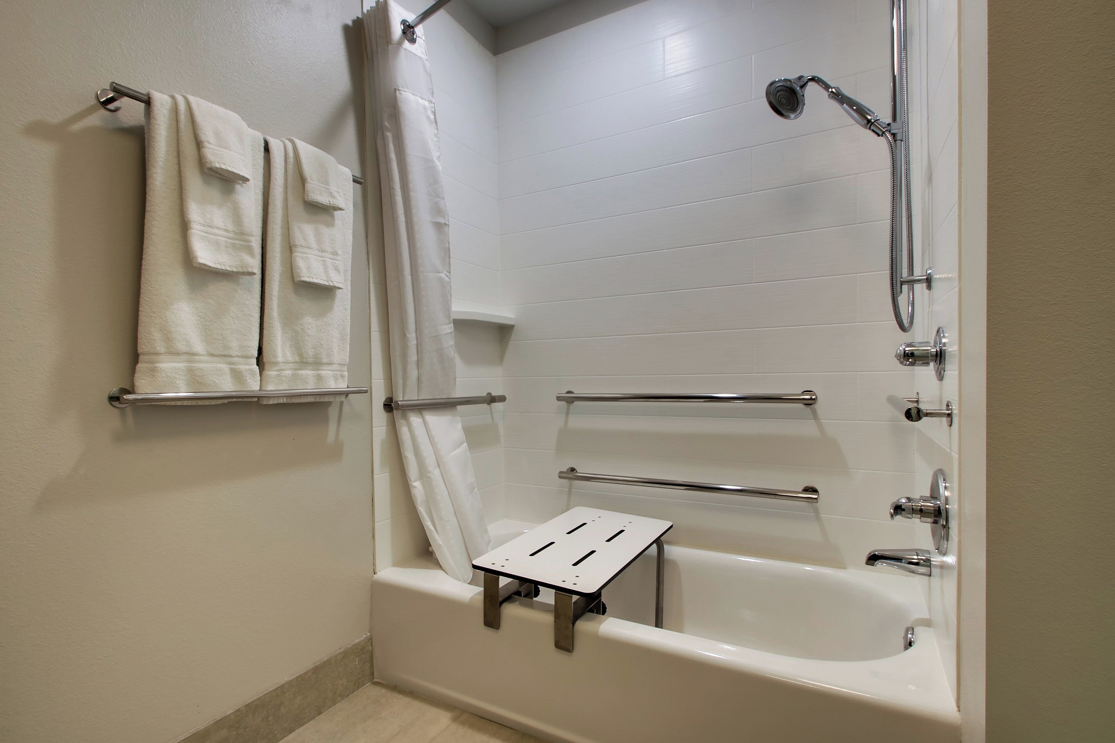 Un baño con bañera, ducha y un taburete pequeño para facilitar el acceso.