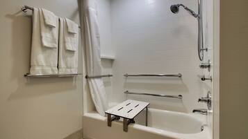 Un baño con bañera, ducha y un taburete pequeño para facilitar el acceso.