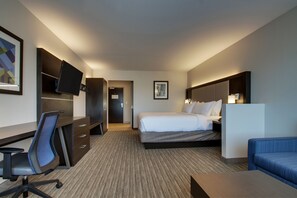 Une chambre d’hôtel avec un lit, un bureau, une chaise et un téléviseur fixé au mur.
