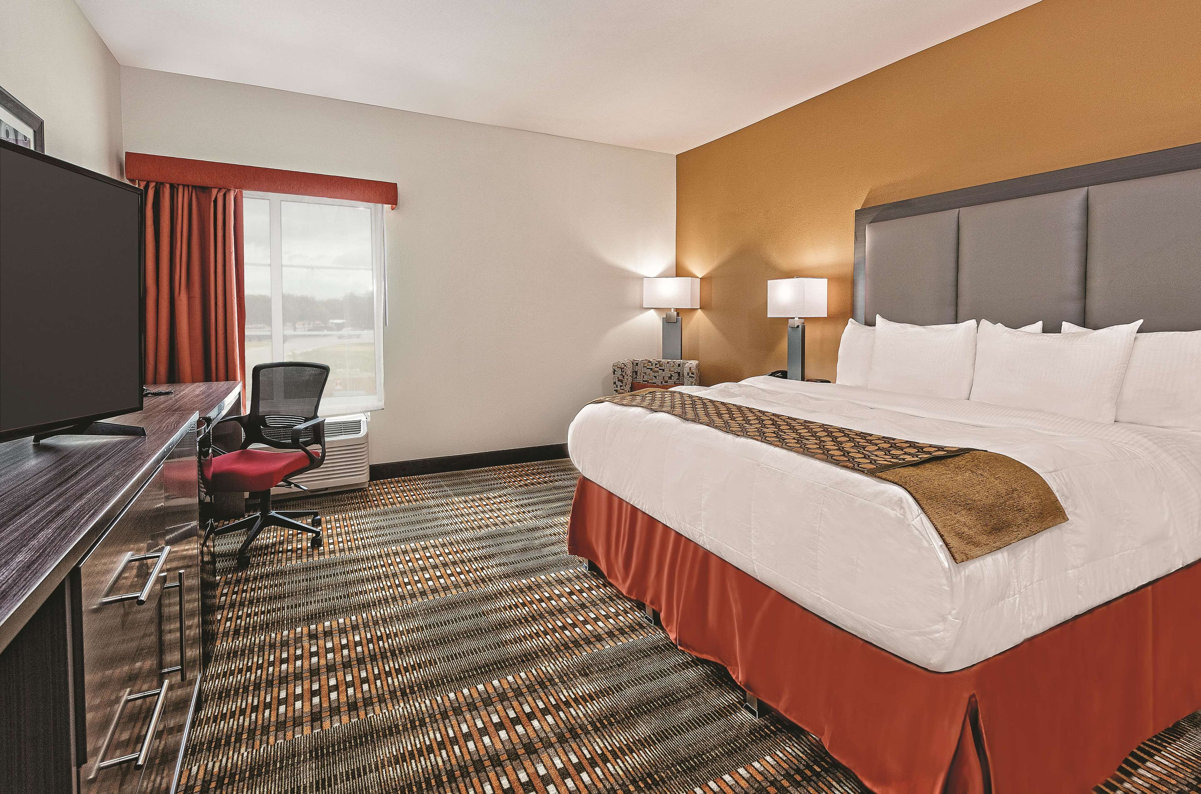 Habitación de hotel con cama, escritorio, silla y televisor.