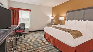 A hotel room with a bed, desk, chair, and a television.