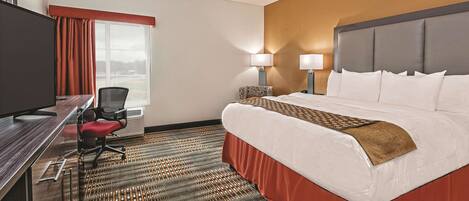 A hotel room with a bed, desk, chair, and a television.