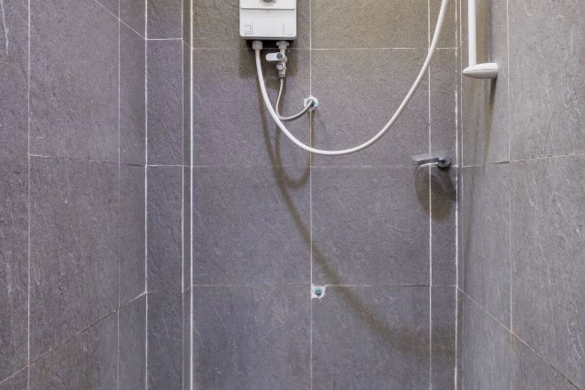 A shower area with a control panel and a handheld showerhead.