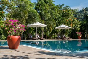 Una piscina al aire libre, sombrillas, tumbonas
