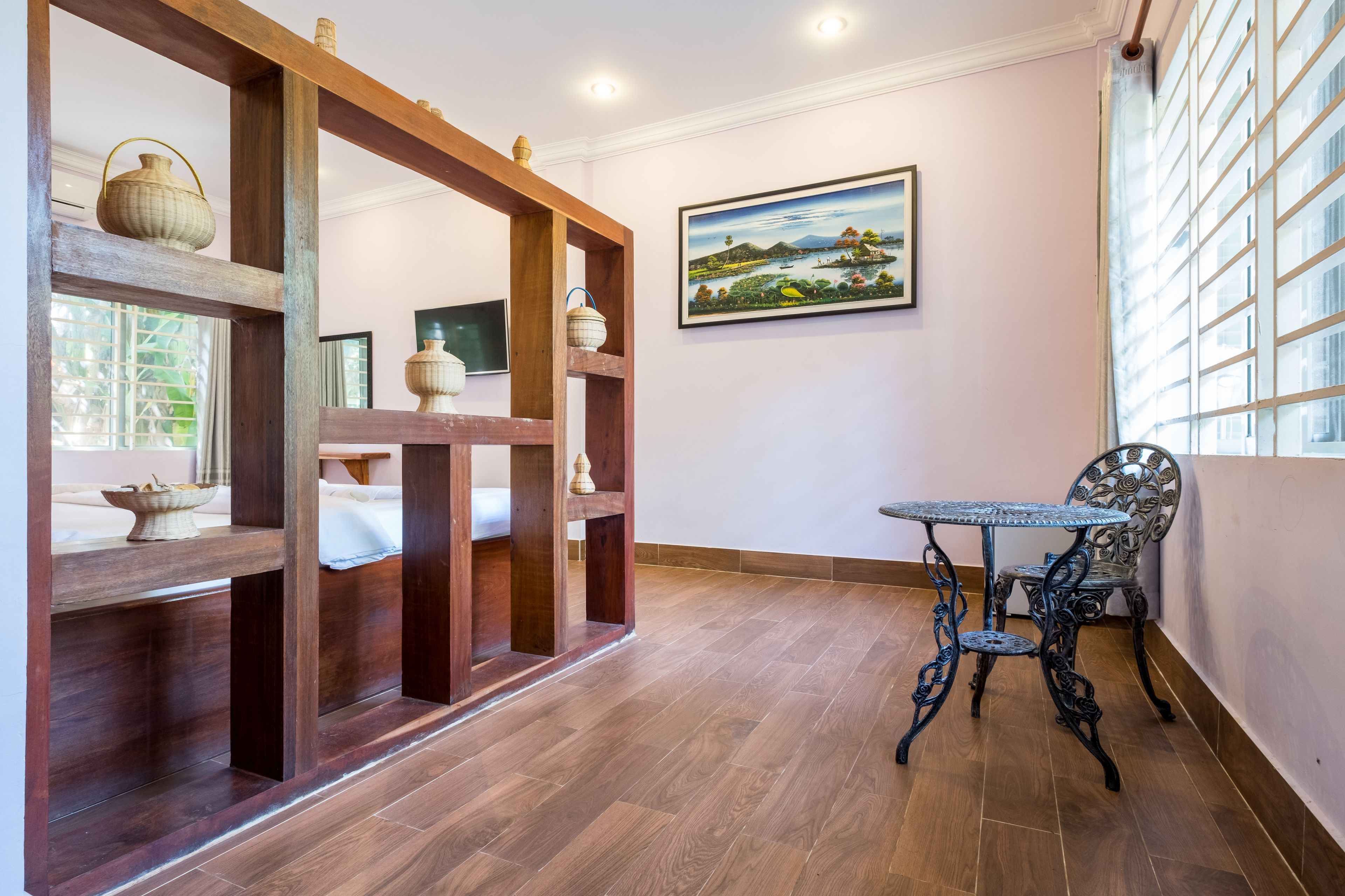 A room with a wooden partition, a table, and a chair. There is a painting on the wall and a window with blinds.