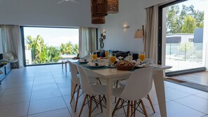 A dining area with a table set for breakfast, including fruits, bread, and juice glasses.