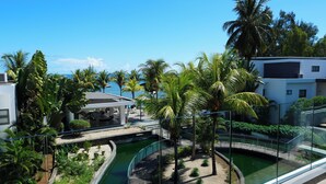 Un complex turístic amb piscina, palmeres i vista al mar.