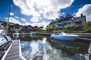 Un puerto deportivo con barcos amarrados, un muelle de madera y edificios modernos de varios pisos con balcones.