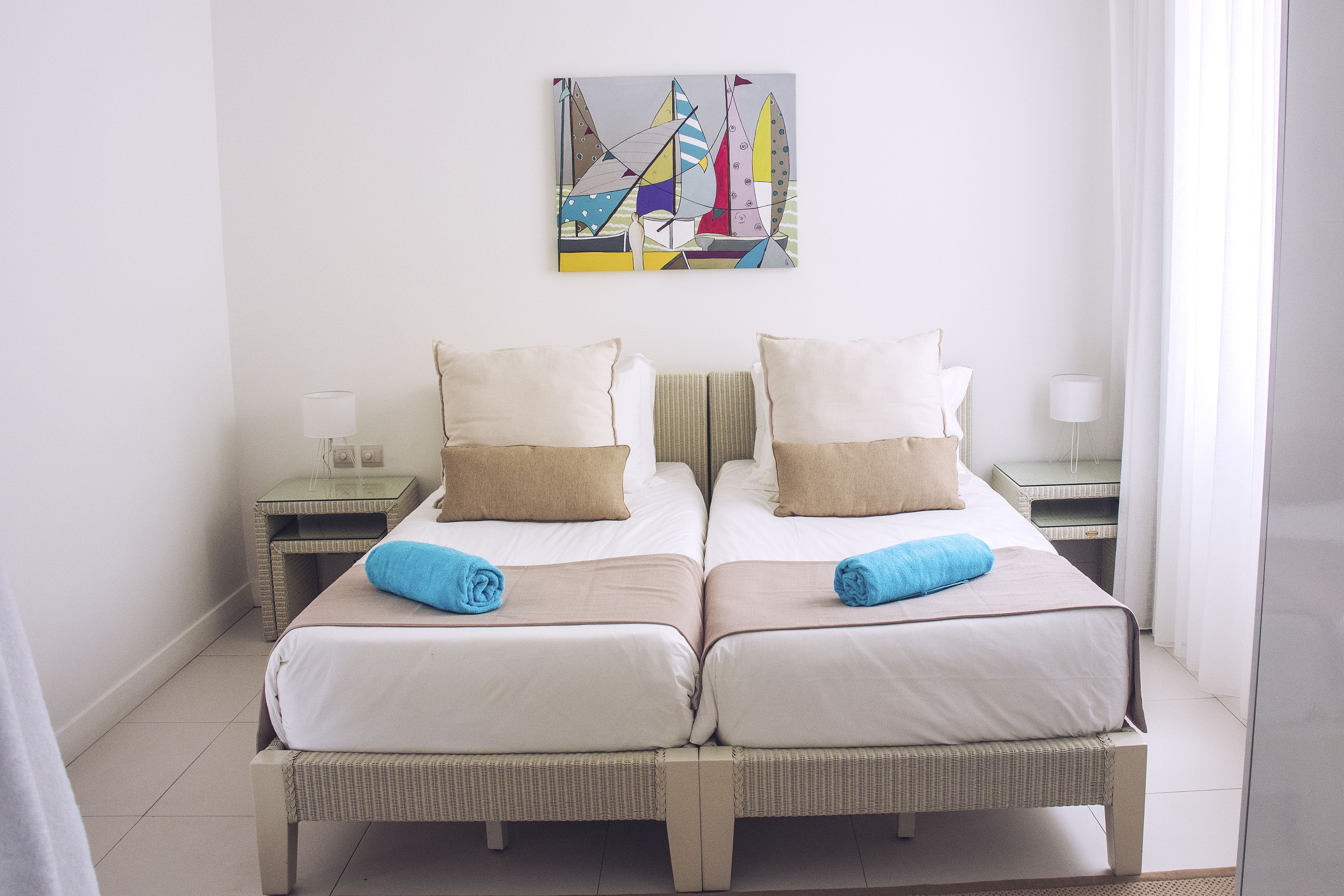 Una cama doble con dos almohadas, una mesita de noche con lámpara y una obra de arte en la pared.