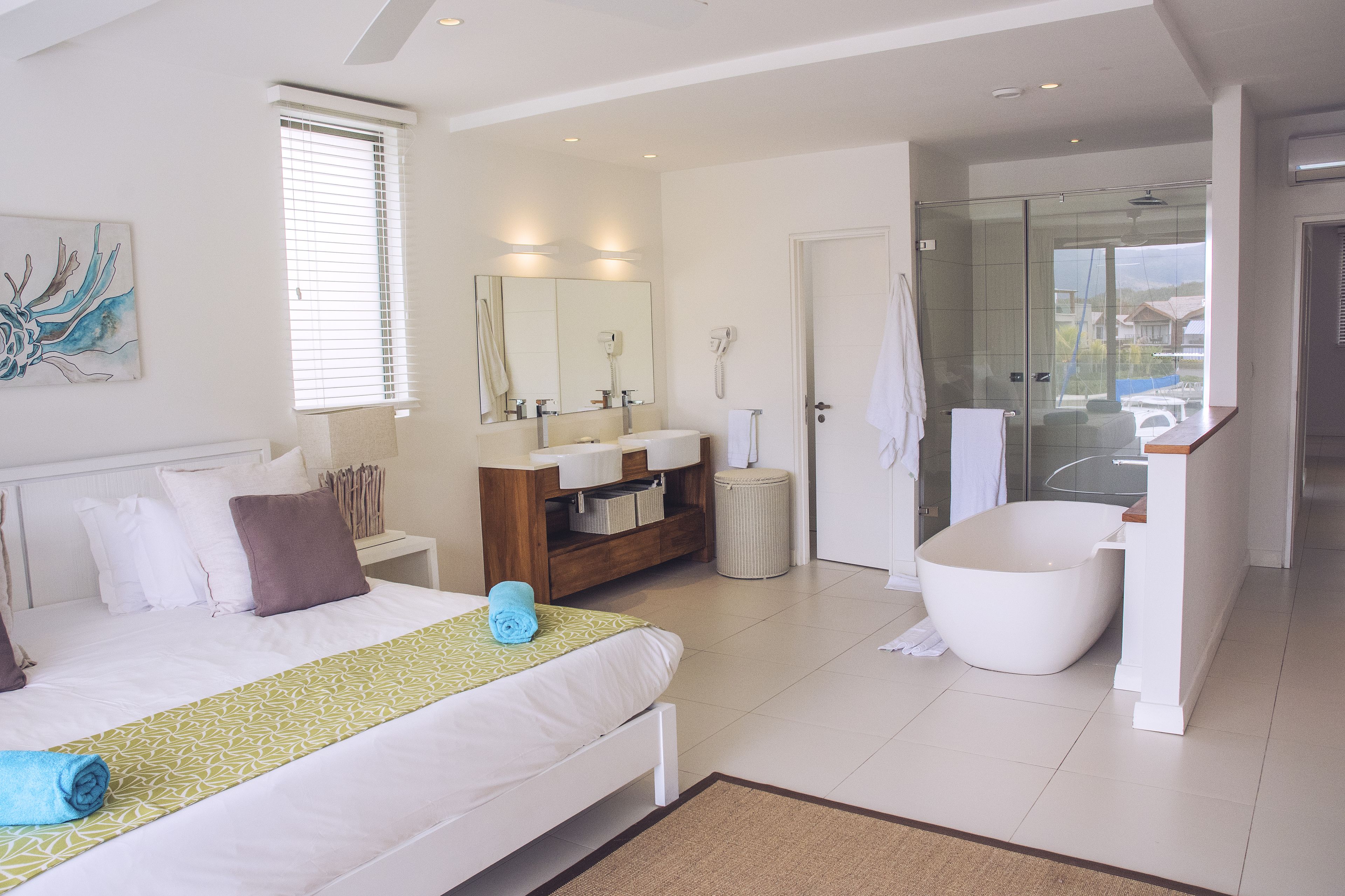 A modern hotel room with a large bed, a bathroom with a bathtub, and a shower area.