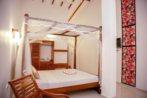 Una cama con dosel y columnas, muebles de madera, una mesita de noche y un espejo.