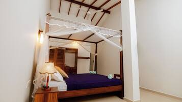 Une chambre à coucher avec un lit à baldaquin en bois, une table de chevet avec une lampe et un ventilateur de plafond.