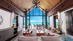 Un salón moderno con un amplio ventanal que ofrece vistas al mar.