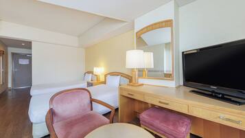 A hotel room with a bed, a desk with a television, a chair, a lamp, and a mirror.