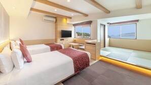 A hotel room with two beds, a desk, a television, and a view of the sea. - Wan Wan Paradise Toba (Toba)