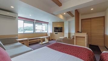 A modern hotel room with a large bed, a sofa, a desk, and a TV.
